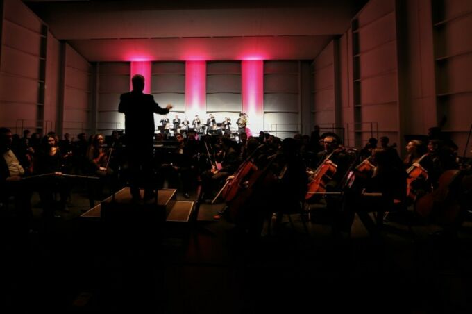 pink lights on stage with conductor and orchestra silhouette