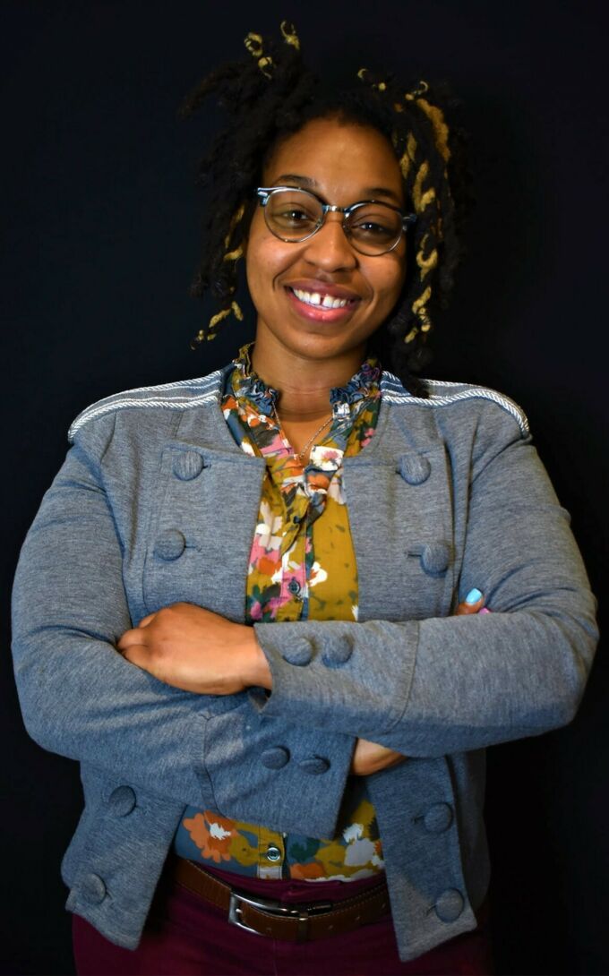A photograph of Chadijah Craig smiling with her hands crossed.
